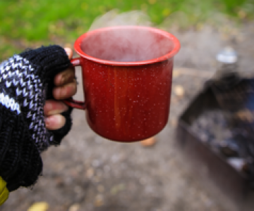 Gloved hand with a mug of something hot